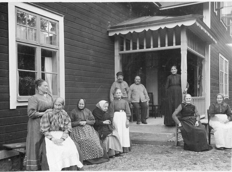 Utanför ålderdomshemmet Solliden år 1911. Framför fönstret står föreståndarinnan Emmy Nykvist och på trappan står Lilla Augusta och håller om stolpen.Mannen med mössan , Niklas Nilsson bodde vid Minsjö. Han spelade fiol och kallades för Nisse i Korskullen.